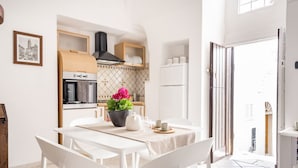 A modern kitchen with white cabinetry, a built-in oven, and a black range hood.