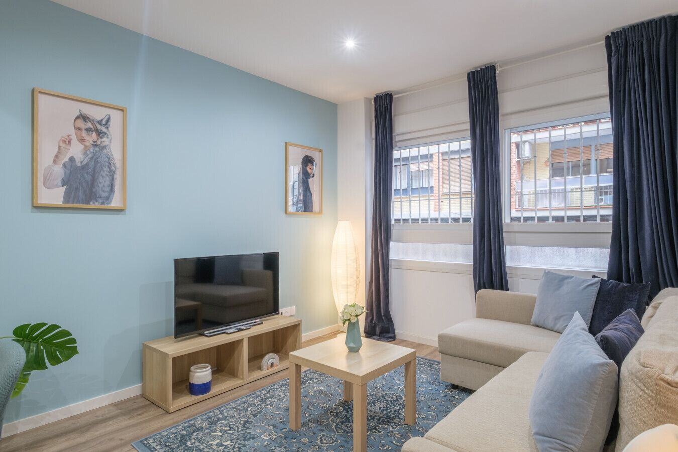 Ein Wohnzimmer mit Fernseher, Sofa und einem Fenster mit Vorhängen.