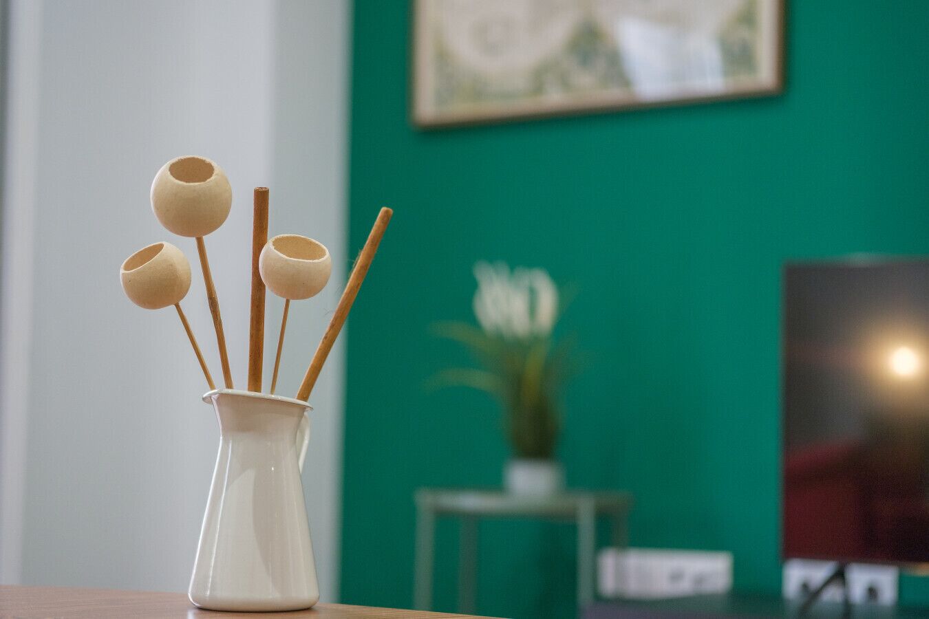 Un vaso bianco con bastoncini di legno e tazze di ceramica su un tavolo in legno.