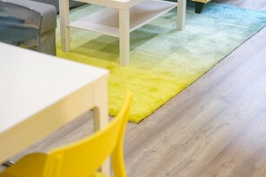 A room with a wooden floor, a yellow chair, and a white table.
