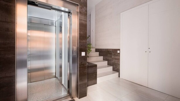 A modern elevator with a metallic finish, a staircase with a minimalist design, and a plain door. - Bright, Clean & Very Comfortable Apartment (Valencia)