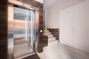 Un ascensore moderno con finiture metalliche, una scala dal design minimalista e una porta semplice.