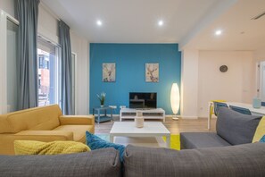 A modern living room with a blue accent wall, a sofa, a coffee table, and a TV.