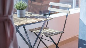 A small wooden table with a potted plant, a foldable chair, and a window with a view of a brick building. - Modern, Stylish Apartment (Valencia)