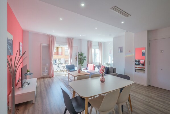 A modern living room with a dining area, large windows, and a view of the outside.