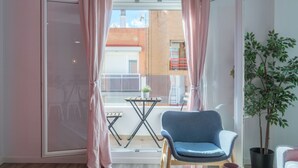 A room with a sliding glass door leading to a balcony, a blue chair, a small table, and a potted plant. - Modern, Stylish Apartment (Valencia)
