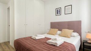 A bedroom with a bed, pillows, a bedside table, a lamp, and a wardrobe. - Modern, Stylish Apartment (Valencia)