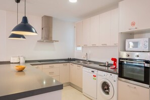 Una cocina moderna con lavadora integrada, microondas y horno.