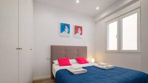 A bedroom with a bed, two pillows, a blue blanket, and two wall art pieces. - Spacious Clean & Colourful Apt Quiet Zone (Valencia)