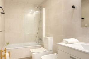 Une salle de bain moderne avec une douche à parois de verre, des toilettes blanches et un lavabo blanc.