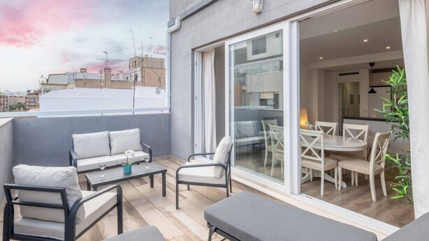A modern balcony with a sofa, chairs, and a dining table.