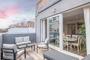Un balcon moderne avec un canapé, des chaises et une table à manger.
