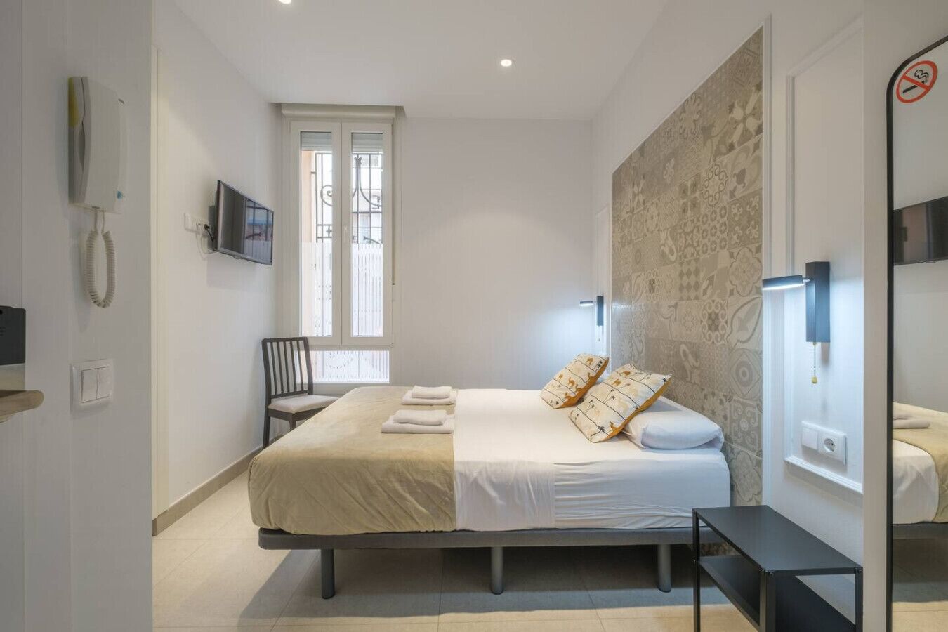A modern bedroom with a large bed, a chair, a TV, and a window with a view.