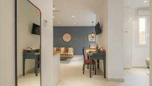 A modern living room with a sofa, a dining table, and chairs. There is a flat-screen TV mounted on the wall. - ꕥ Chic & Comfortable Apartment/ Private Terrace ꕥ (Valencia)