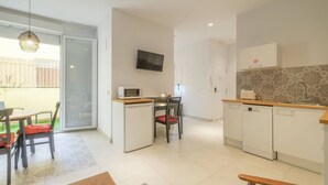 A compact kitchen with a microwave, a small dining table with chairs, a TV mounted on the wall, and a patterned backsplash. - ꕥ Chic & Comfortable Apartment/ Private Terrace ꕥ (Valencia)