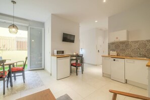A compact kitchen with a microwave, a small dining table with chairs, a TV mounted on the wall, and a patterned backsplash. - ꕥ Chic & Comfortable Apartment/ Private Terrace ꕥ (Valencia)