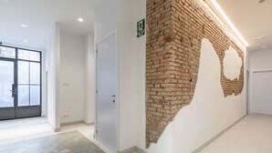 A hallway with a brick wall, a door, and a sign indicating an exit. - ꕥ Chic & Comfortable Apartment/ Private Terrace ꕥ (Valencia)
