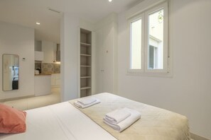 A bedroom with a bed, a wardrobe, a mirror, and a window.