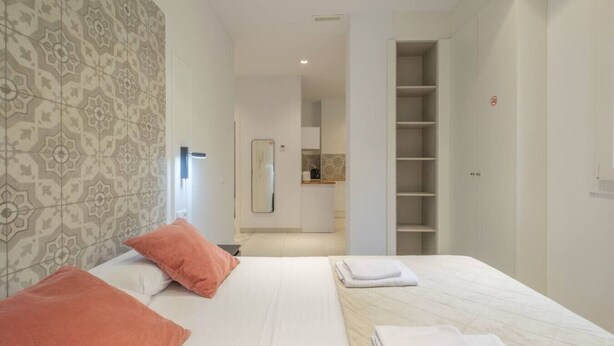 A hotel room with a bed, two pillows, a bedside table, a mirror, and a wardrobe. - ꕥ Chic & Comfortable Apartment/ Private Terrace ꕥ (Valencia)