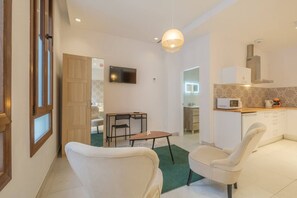 Una sala de estar moderna con comedor, cocina y televisor montado en la pared.
