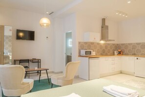 Una habitación de hotel compacta con kitchenette, comedor y zona de estar.