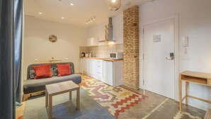 Una sala de estar moderna con un sofá, una mesa de centro y una zona de cocina con microondas y armarios.
