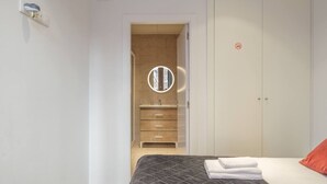 Un dormitorio con cama, armario, baño con espejo y una puerta.