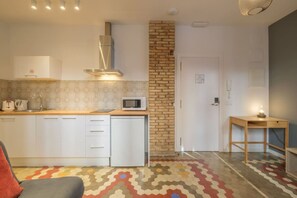 Une cuisine de taille réduite avec des meubles blancs, un four à micro-ondes et un mur décoratif en briques.