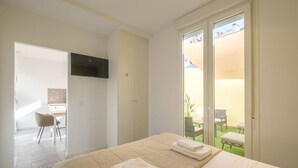 A hotel room with a bed, a TV, a desk, and a view of the outdoor patio. - Marvellous Apt. with a Large Private Terrace (Valencia)