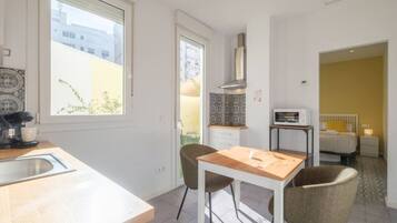 Una cocina moderna con una mesa y sillas de madera, horno empotrado y ventana con vista a un paisaje urbano.