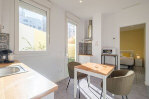 A modern kitchen with a wooden table and chairs, a built-in oven, and a window overlooking a cityscape.