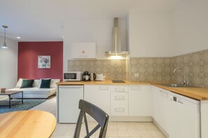 A compact kitchen with white cabinets, a microwave, a coffee maker, and a sink.