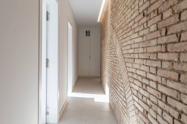A hallway with a brick wall on one side and a white door on the other.