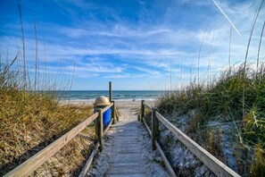 A wooden boardwalk leading to a beach with a clear sky.