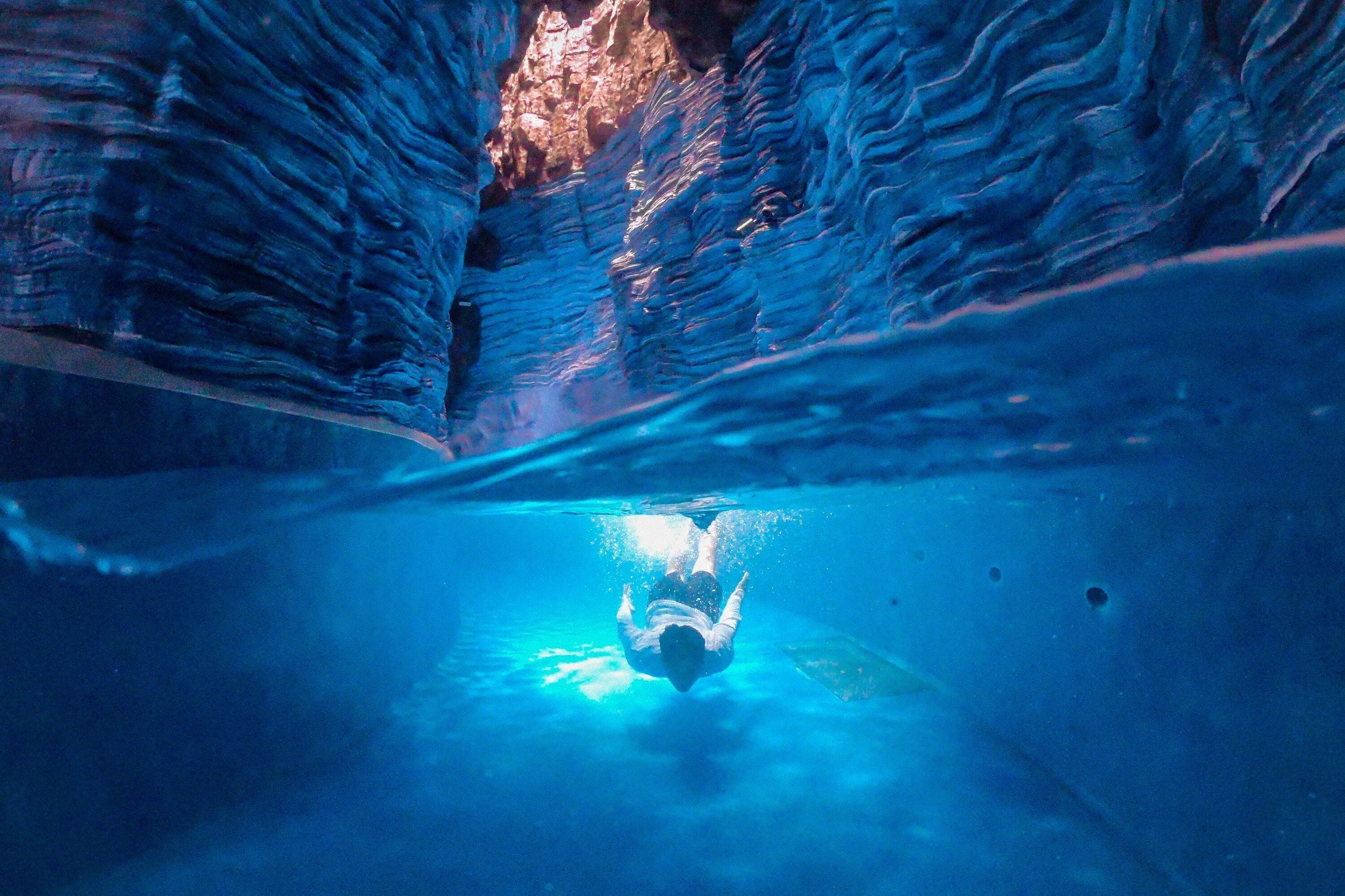 An underwater scene with a person swimming in a tunnel.