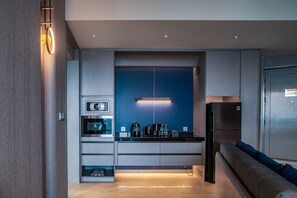 A modern kitchen with built-in appliances, a blue accent wall, and a seating area with a sofa and cushions.