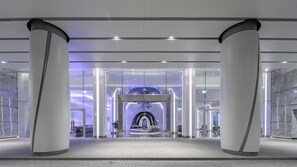 A modern hotel lobby with a spacious entrance, large columns, and a futuristic design.