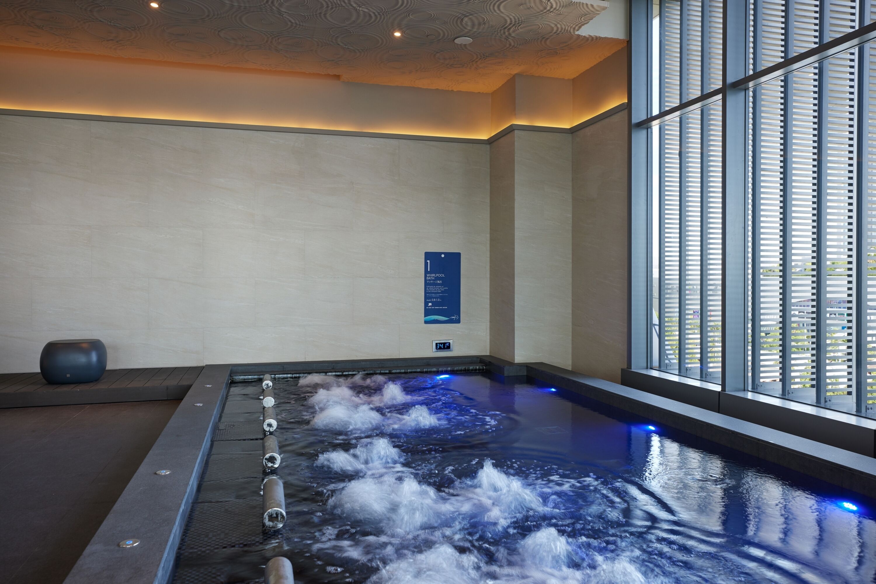 A spa area with a hot tub, a sign indicating room number 1, and a window with blinds.
