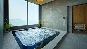 A modern spa room with a large hot tub, a view of the sea, and a wooden sauna area. - Grande Centre Point Space Pattaya (Pattaya)