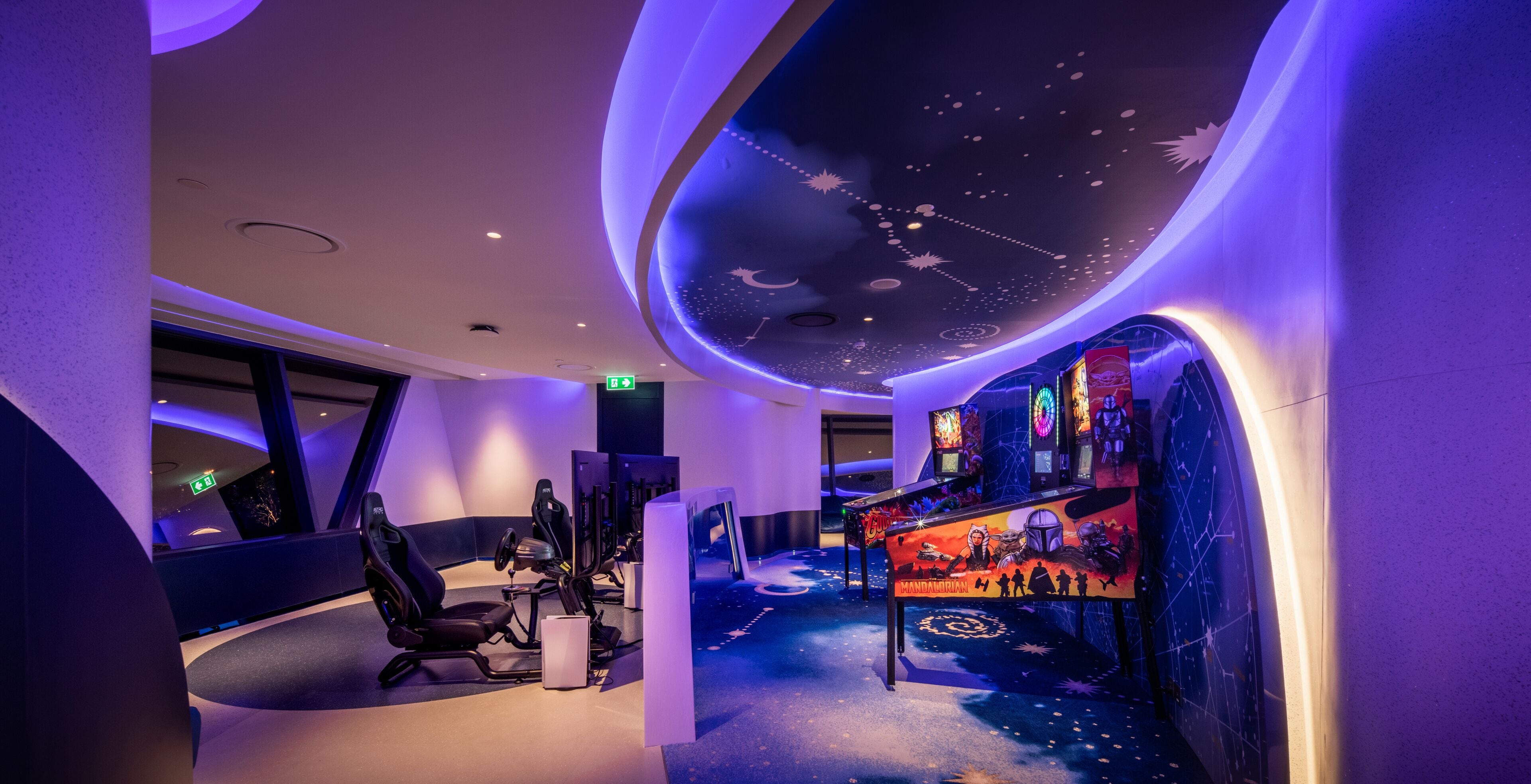 A room with exercise equipment, a ceiling with a starry design, and a wall with a space-themed mural.