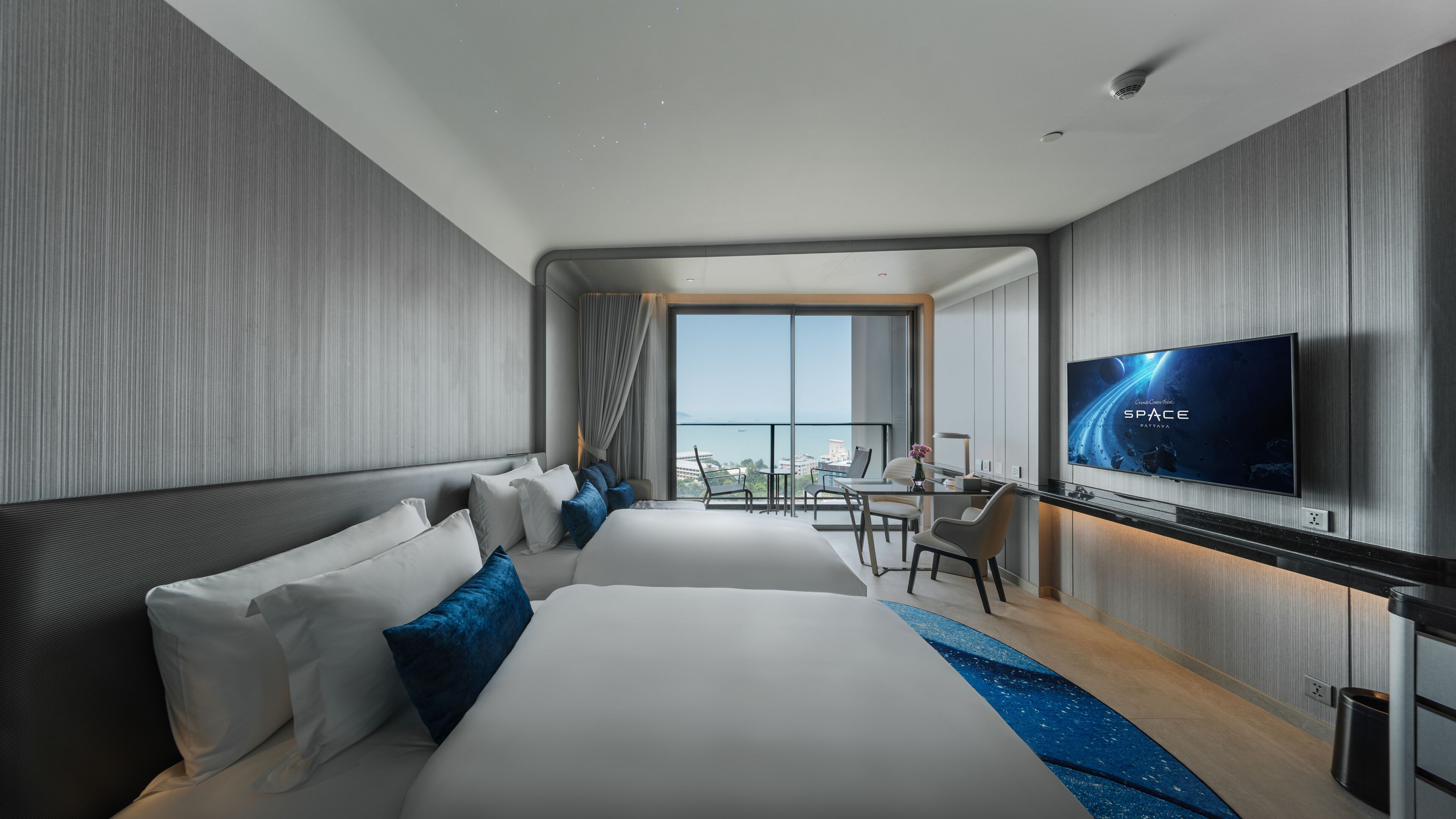 Una habitación de hotel moderna con una cama grande, un escritorio y un televisor.