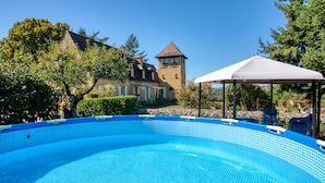 A swimming pool with a tiled edge, a gazebo, and a stone tower in the background. - Magnificent Villa on 50 ha overlooking the medieval town of Domme (Domme)