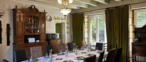A dining room with a table set for six, surrounded by chairs, a wooden cabinet, and a chandelier.