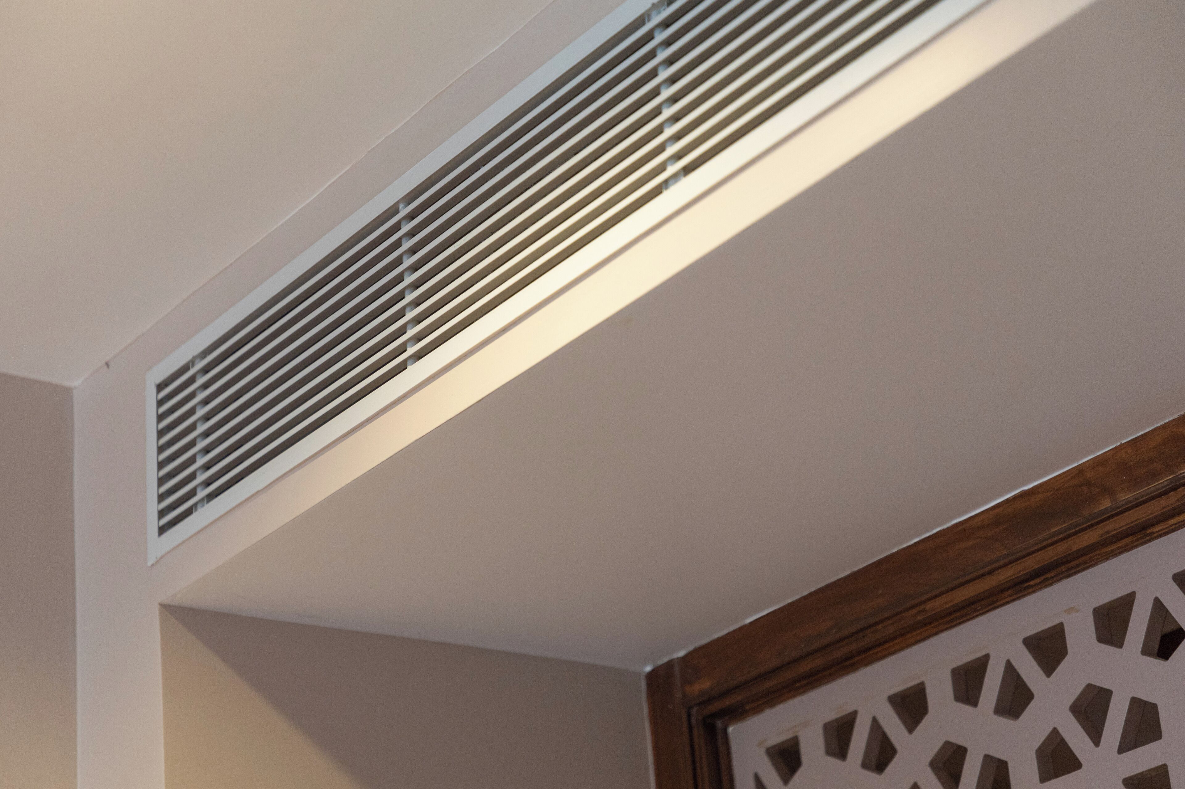 Un techo con una rejilla blanca y un panel decorativo de madera.