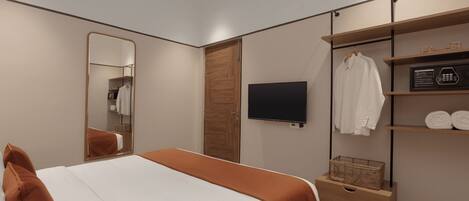 Quarto de hotel moderno com uma cama grande, televisão, guarda-roupa com prateleiras e espelho.