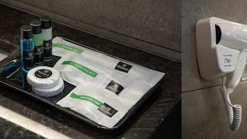 Una encimera de baño con un neceser de afeitar, gorro de ducha y artículos de aseo. Un secador de pelo está fijado a la pared.
