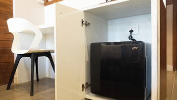 Una cocina compacta con un refrigerador negro, una silla blanca y un gabinete de madera.