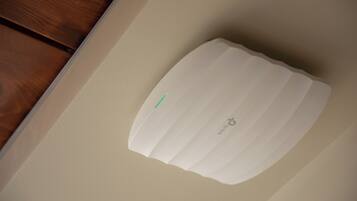 A white, rectangular object with a green stripe, possibly a control panel or device, on a beige wall.