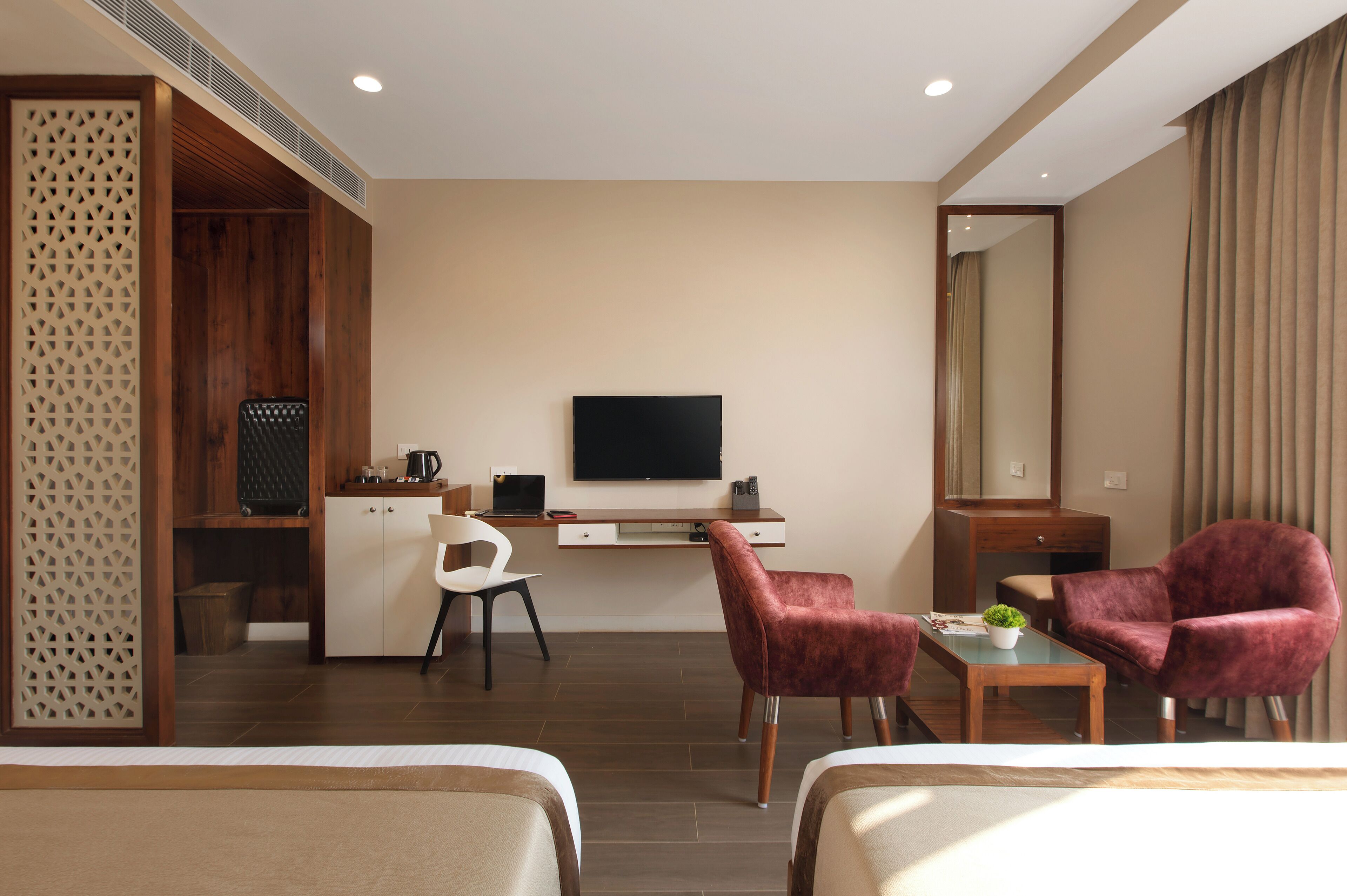 Una habitación de hotel con escritorio, dos sillas, televisión y cama.