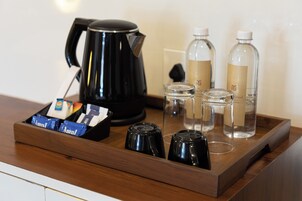 A tray with a black coffee maker, two glass bottles, and a box of Amul biscuits.